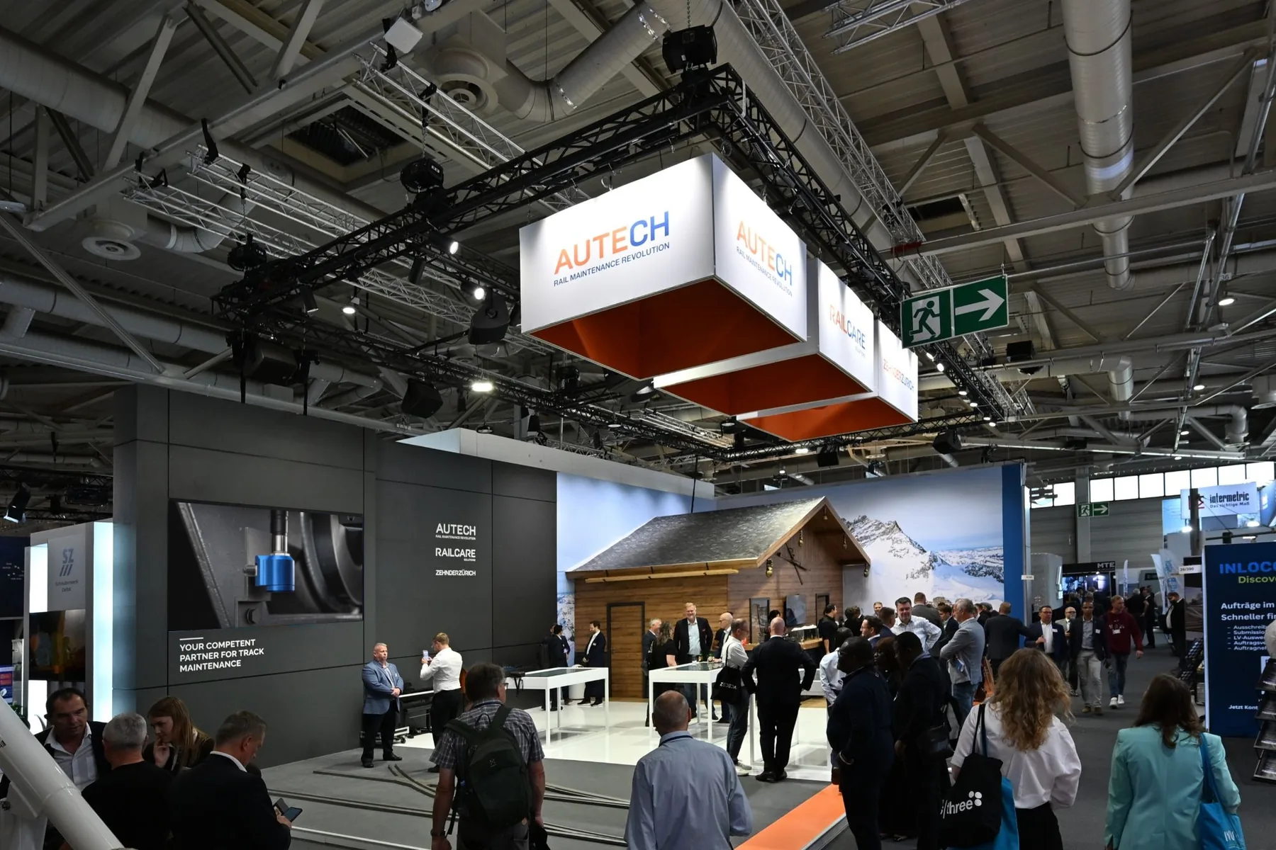 The shared stand of Autech, Railcare and Zehnder Zürich at InnoTrans 2026, with visitors in front of the alpine hut