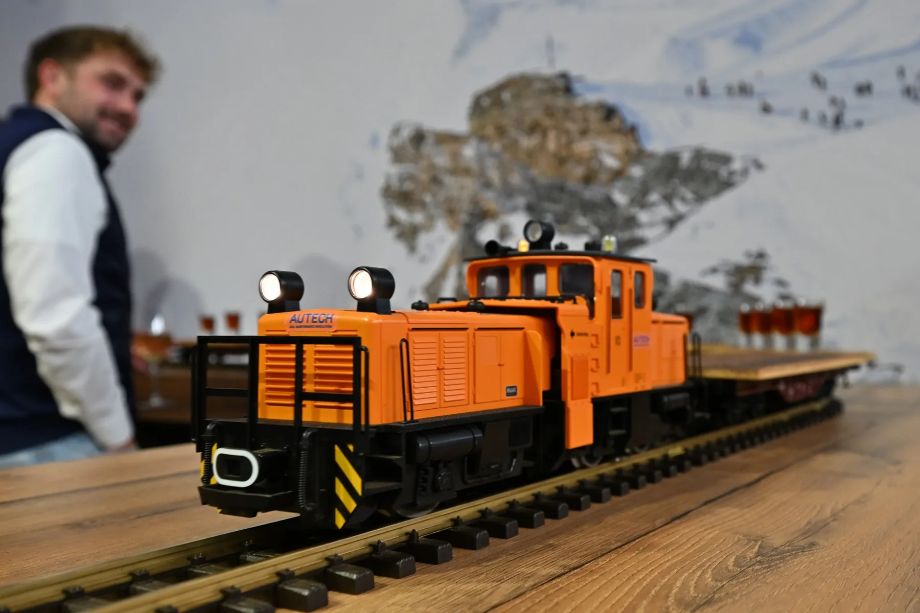 The Food Train: an orange model locomotive pulling a flat wagon with glasses along the bar